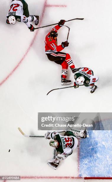 Andrew Desjardins of the Chicago Blackhawks falls on the ice as goalie Darcy Kuemper of the Minnesota Wild reaches out for the puck at the United...