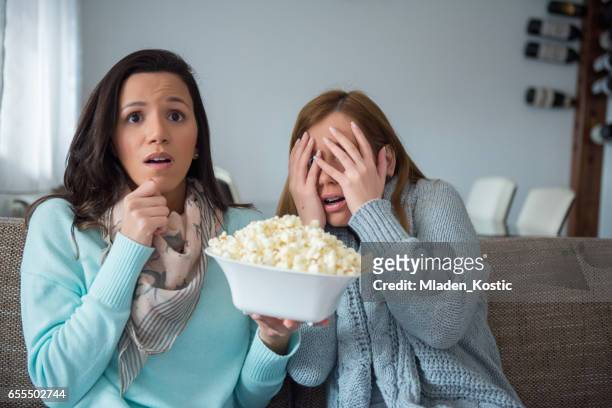 two women watching tv together, horror movie - weird roommate stock pictures, royalty-free photos & images