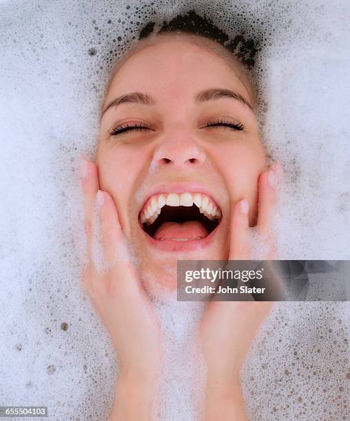 portrait of woman laughing in bubble bath - woman bath tub wet hair stock pictures, royalty-free photos & images