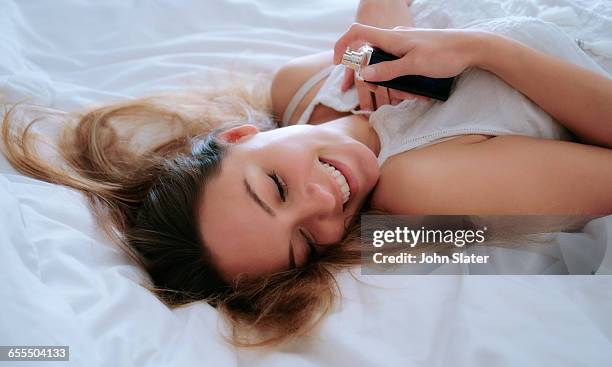 woman smiling holding perfume bottle - 香水 個照片及圖片檔