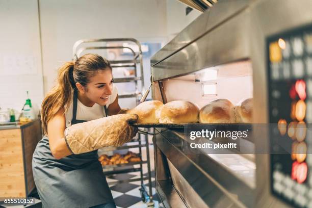 baker tar det varma brödet ur kaminen - bakning business bildbanksfoton och bilder