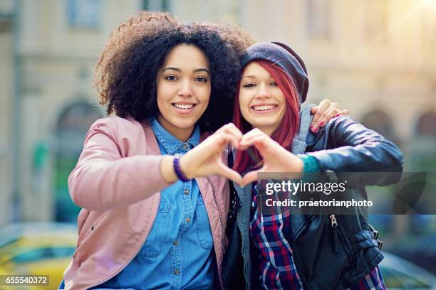 two girlfriends making heart with their hands on the street - hands in heart shape stock pictures, royalty-free photos & images