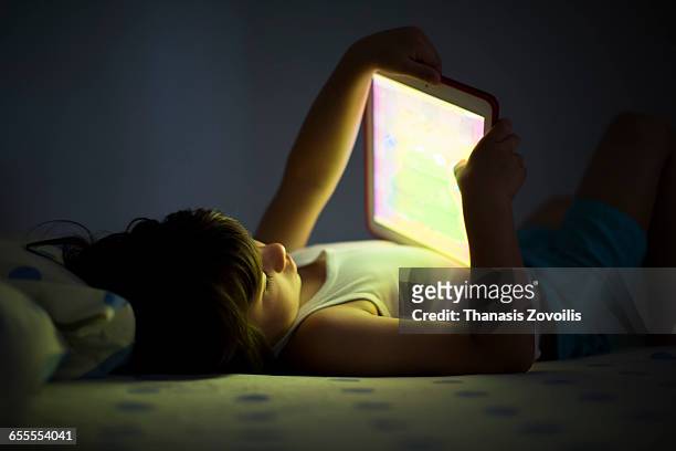 5 year old boy using a digital tablet in the dark - children ipad stock pictures, royalty-free photos & images