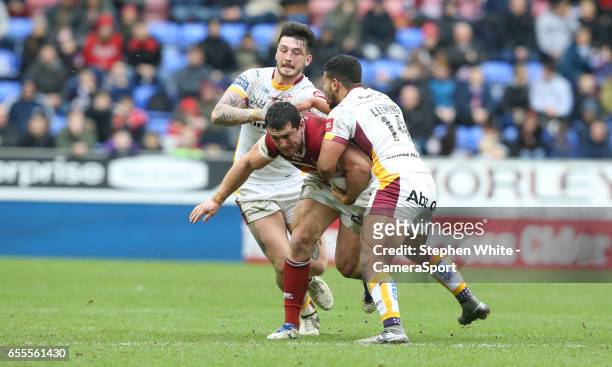 Wigan Warriors' Ben Flower is tackled by Huddersfield Giants' Oliver Roberts and Kruise Leeming during the Betfred Super League Round 5 match between...