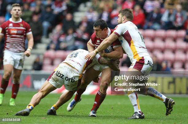 Wigan Warriors' Ben Flower is tackled by Huddersfield Giants' Sam Rapira and Paul Clough during the Betfred Super League Round 5 match between Wigan...