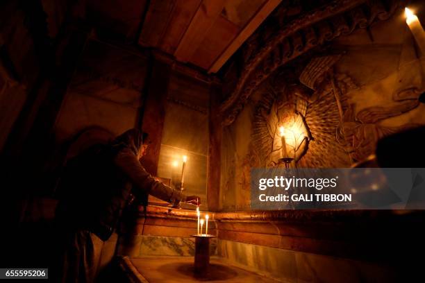 Picture taken at the Church of the Holy Sepulchre in Jerusalem's old city on March 20 shows a Christian worshipper praying inside the Edicule...
