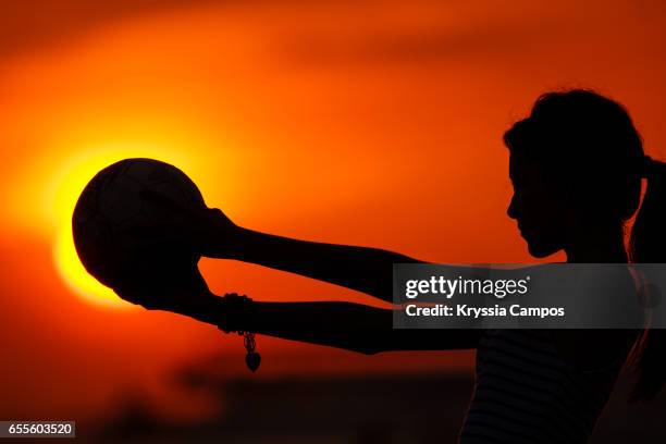 girl holding soccer ball against the sun at sunset - eclipse fotografías e imágenes de stock