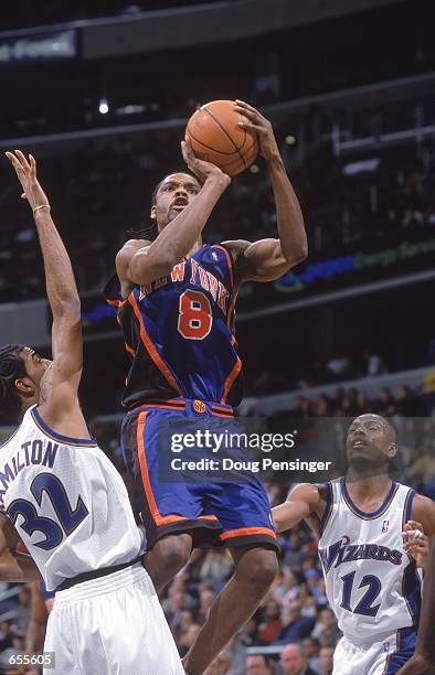 Latrell Sprewell of the New York Knicks takes a shot at the basketas he is double teammed by Chris Whitney and Richard Hamilton of the Washington...