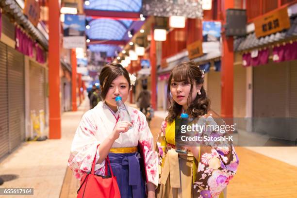 hoge-tiener meisjes in hakama frisdrank drinken in fles - asian female friends drinking soda outdoor stockfoto's en -beelden