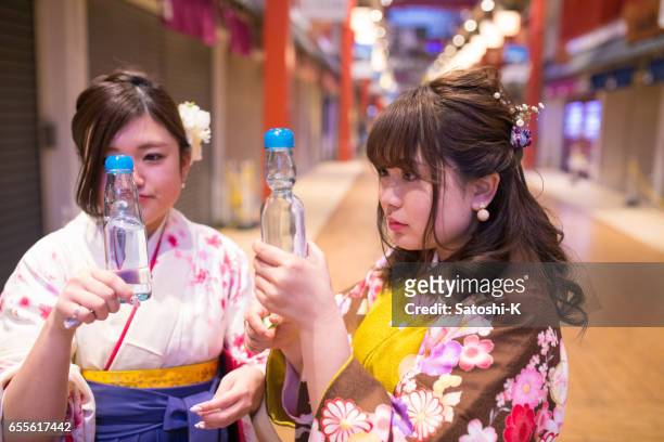 hoge-tiener meisjes in hakama kijkend naar een fles frisdrank - asian female friends drinking soda outdoor stockfoto's en -beelden