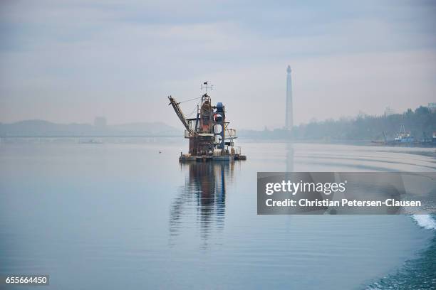 dredging barge and juche tower on taedong river - taedong river stock pictures, royalty-free photos & images