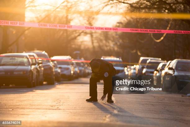 Chicago Police Officer collects shell casings at the crime scene of a shooting that left three people injured on the 3200 block of Maypole Avenue,...