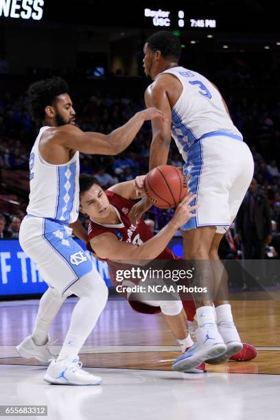 Dusty Hannahs of the University of Arkansas loses possession of the ball after colliding with Kennedy Meeks and Joel Berry II of the University of...