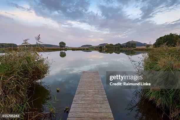 wooden jetty with reflective sky in lake - thuringia foto e immagini stock