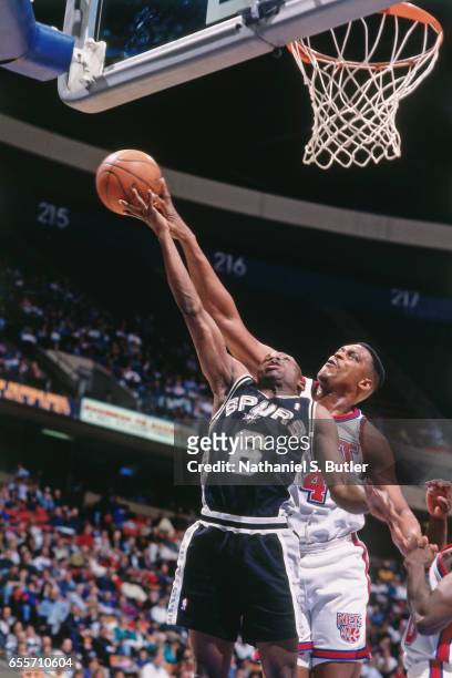 Rick Mahorn of the New Jersey Nets blocks a shot against Avery Johnson of the San Antonio Spurs circa 1993 at the Contintental Airlines Arena in East...