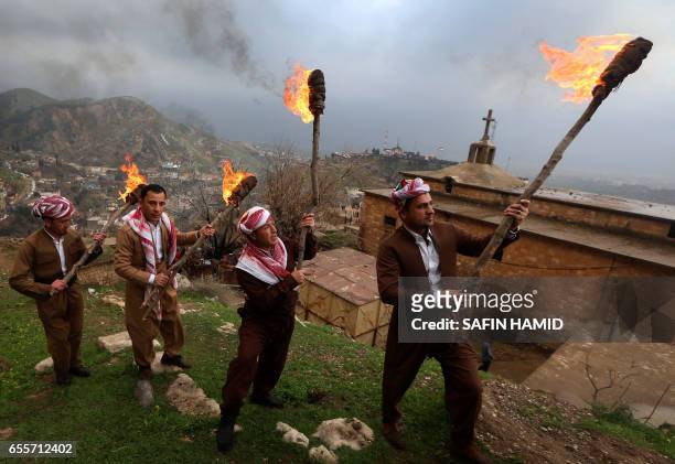 Iraqi Kurds holding lit torches walk up a mountain in the town of Akra, 500 km north of Baghdad, on March 20, 2017 as they celebrate the Noruz spring...