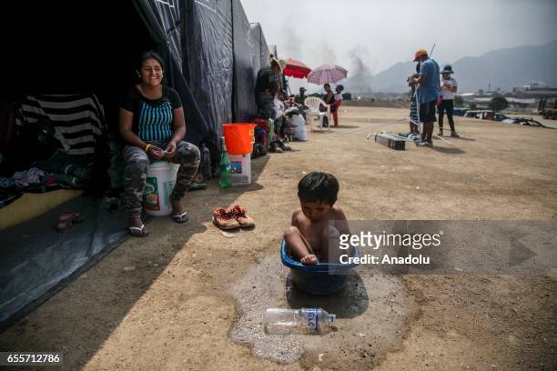 Boy, who is a flood victim, is seen in a bucket near a tent set up with the help of volunteers and authorities in the Huachipa district, east of...
