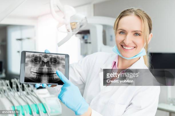young dental expert showing x-ray on tablet - dental record stock pictures, royalty-free photos & images