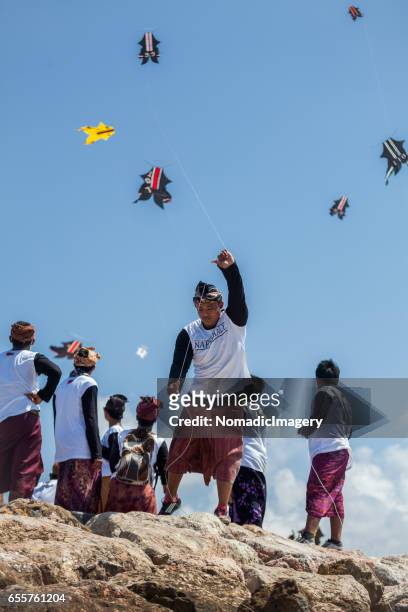 man tugs kite flying line during kite competition in bali - indonesian kite stock pictures, royalty-free photos & images