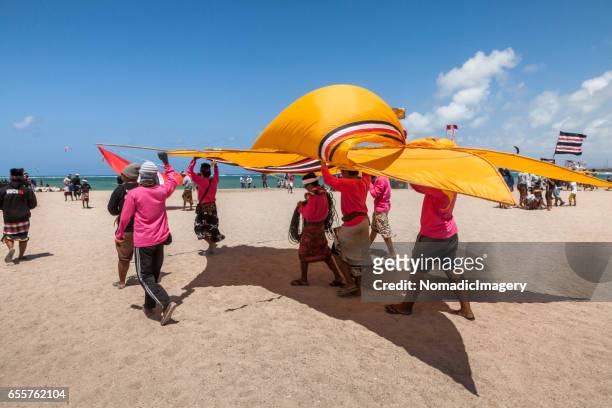 huge yellow kite being carried on a bali beach - indonesian kite stock pictures, royalty-free photos & images