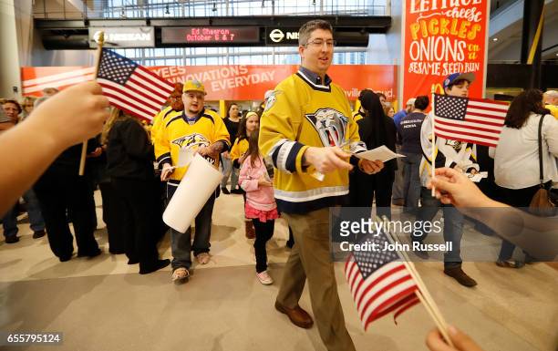 Nashville Predators fans receive American flags as they arrive for a game against the Arizona Coyotes during Military Week in the NHL at Bridgestone...