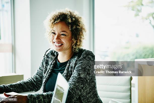 smiling businesswoman in meeting with clients - leanincollection stock pictures, royalty-free photos & images