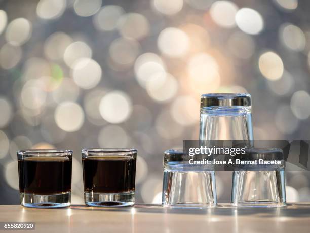 glasses of crystal of chupito one full and another emptiness  , illuminated by the light of the sun - coffee drink stock pictures, royalty-free photos & images