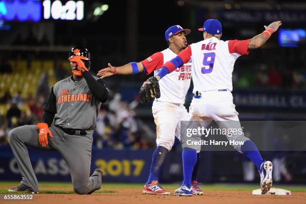 Francisco Lindor and Javier Baez of the Puerto Rico celebrate an inning-ending double play in the 11th as Yurendell Decaster of the Netherlands...