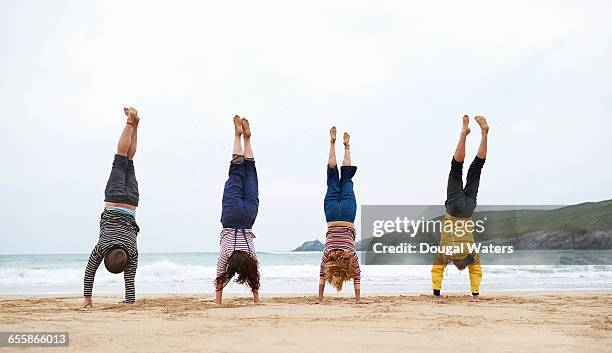 friends doing handstands at beach. - handstand beach stock pictures, royalty-free photos & images