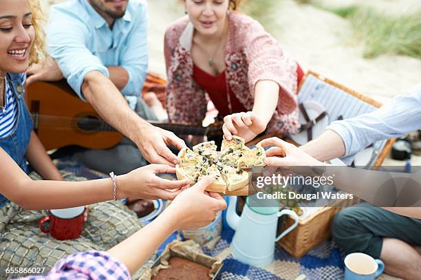 group of friends sharing food at beach picnic. - picknick stockfoto's en -beelden