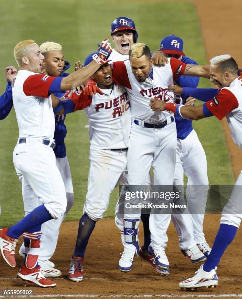 Eddie Rosario is mobbed by teammates after hitting a walk-off sacrifice fly during the 11th inning of Puerto Rico's 4-3 win over the Netherlands in a...