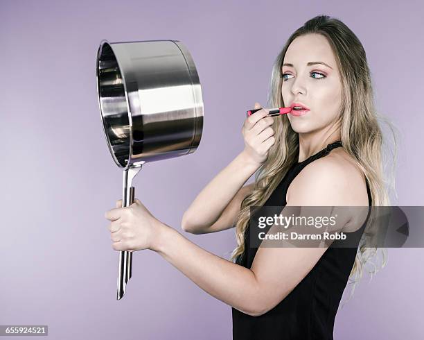 woman using saucepan as a mirror to apply lipstick - holding saucepan stock pictures, royalty-free photos & images