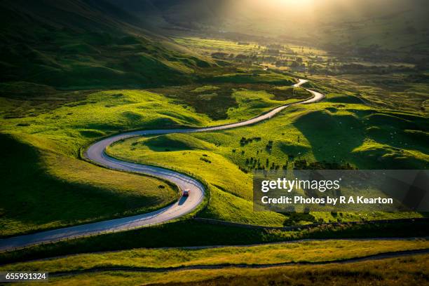 car driving on a bendy road in glorious sunlight - car country road photos et images de collection