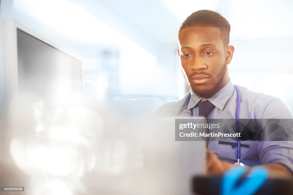 Junior Arzt arbeitet an seinem Schreibtisch in seinem Büro
