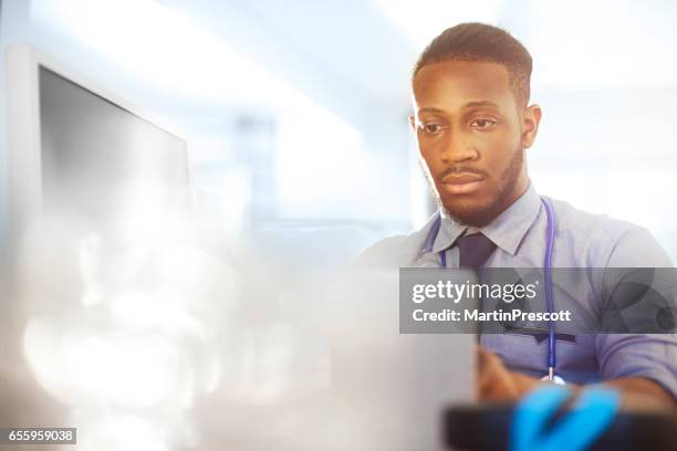 junior doctor working at his desk in his office - hospital paperwork stock pictures, royalty-free photos & images