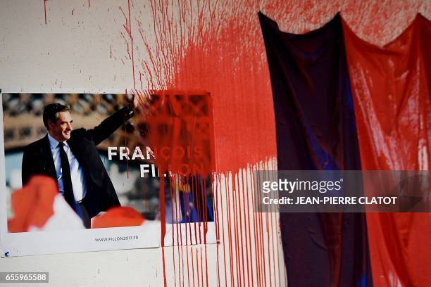Red paint is sprayed and splashed on an election campaign poster of French presidential election candidate for the right-wing Les Republicains party...