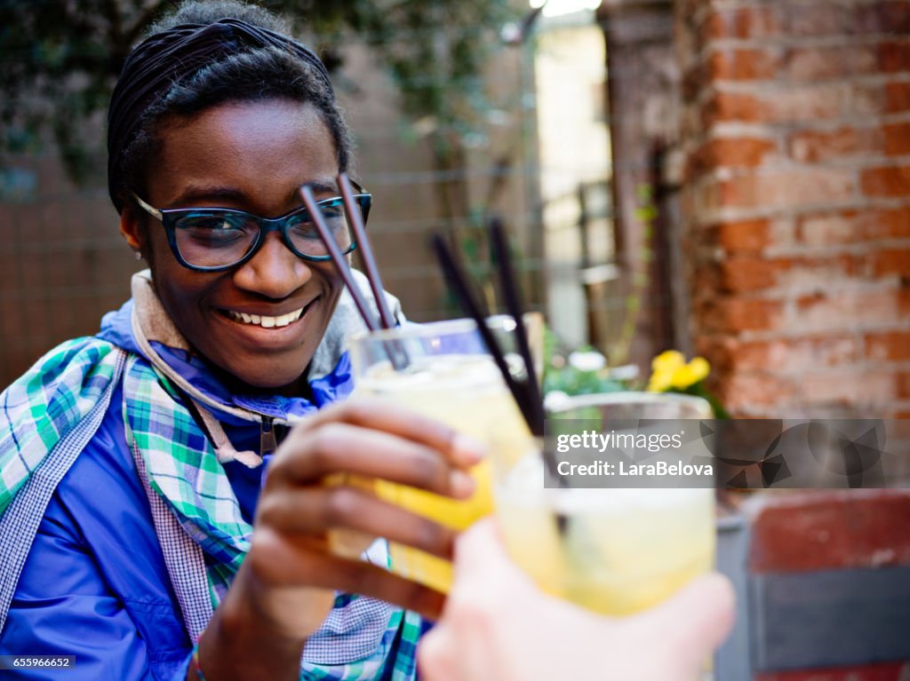 African young woman with cocktail in sidewalk cafe