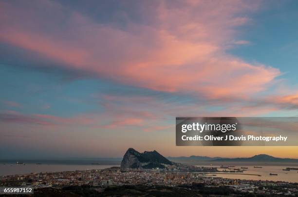 the rock of gibraltar below a dusk sky, with jebel musa mountain and the north african coast visible across the strait of gibraltar - straits of gibraltar stock pictures, royalty-free photos & images