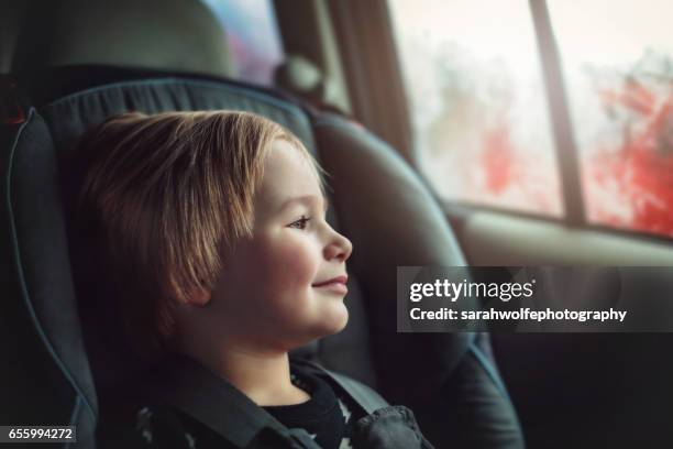 toddler riding in his car seat during a road trip - toddler in car foto e immagini stock