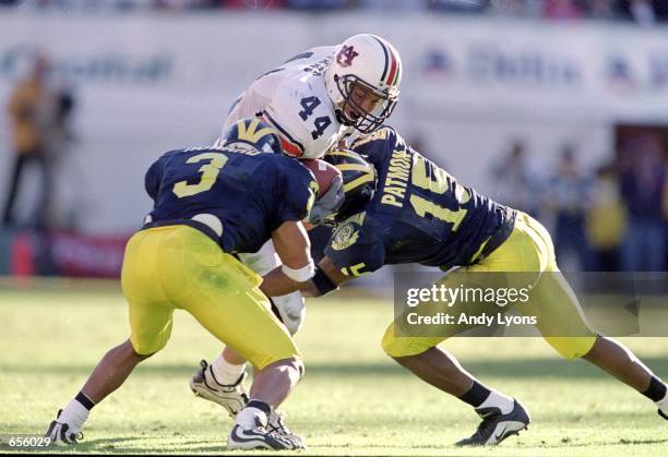 Heath Evans of the Auburn Tigers carries the ball as he is tackled by Todd Howard and Travis Demeester of the Michigan Wolverines during the Citrus...