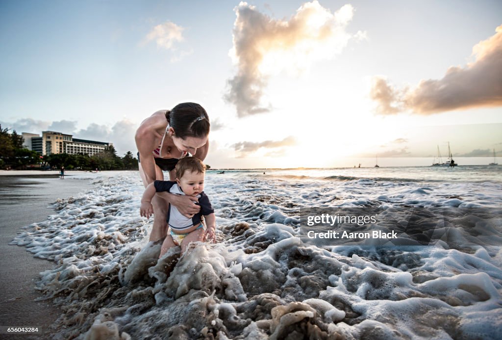 Mom plays with baby in warm gentle surf.