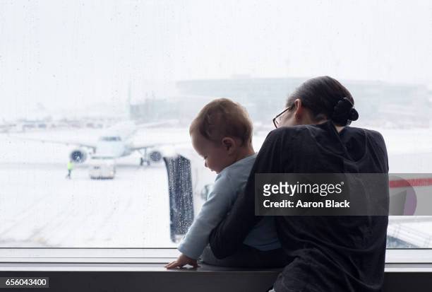 mom and son quiet moment looking at airplanes in the snow. - looking backwards stock pictures, royalty-free photos & images