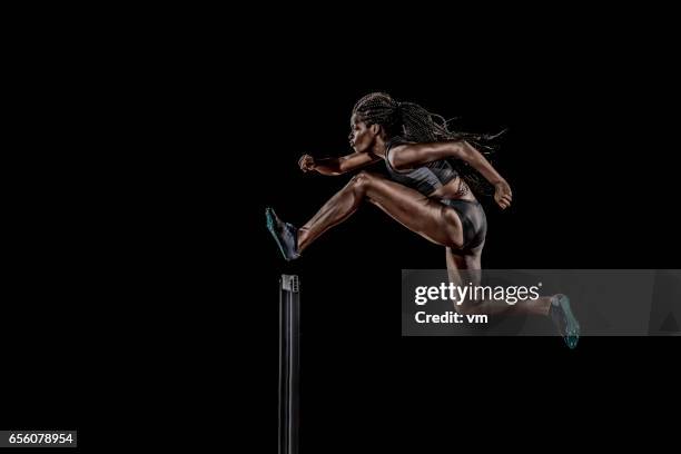 zijaanzicht van een vrouw springen over een hindernis - hordelopen atletiekonderdeel stockfoto's en -beelden