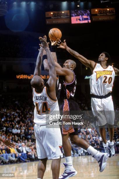 Karl Malone of the Utah Jazz leaps for the basket as he is double teammed by Larry Hughes and Marc Jackson of the Golden State Warriors at The Arena...