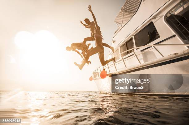 persone giocose che saltano dalla barca in mare. - jumping of boat foto e immagini stock