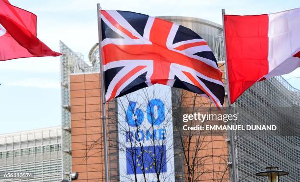 Union Jack flag flies over a banner celebrating the 60th anniversary of "The Treaty of Rome" set up in front of the European Commission, in Brussels...