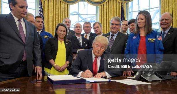 In this handout provided by the National Aeronautics and Space Administration , President Donald Trump, center, signs the NASA Transition...