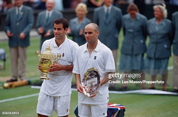 American tennis player Pete Sampras pictured left holding the Gentlemen's Singles Trophy with defeated American tennis player Andre Agassi on right...