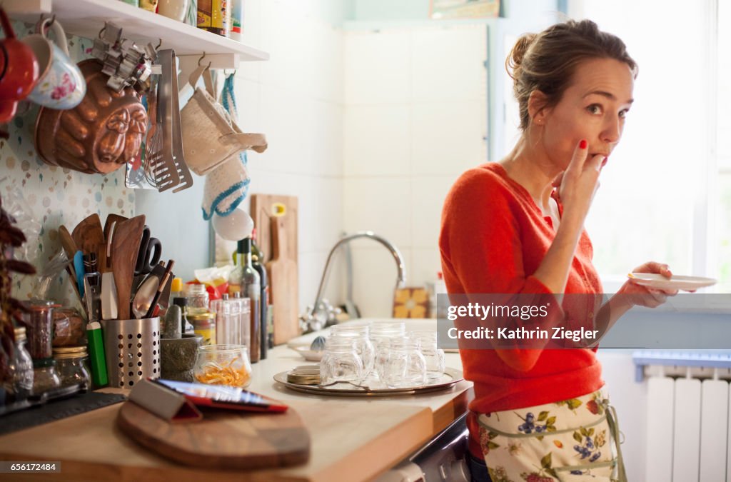 Woman tasting freshly made marmalade from saucer