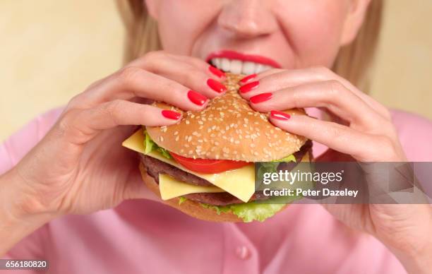 woman biting into hamburger - comfort food stock pictures, royalty-free photos & images